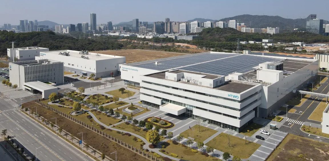 HTWO 광저우 공장 전경 — 태양광 패널을 얹은 흰색 생산동과 주변 도시